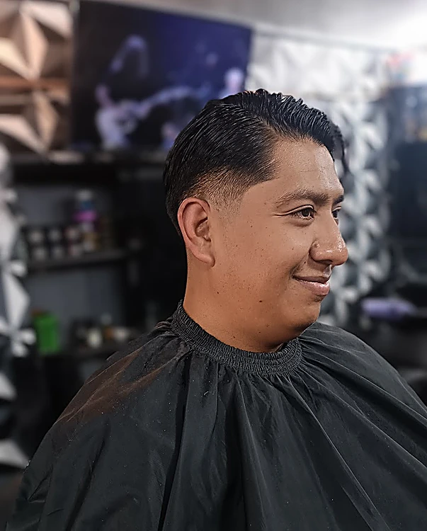 Corte peinado hacia el lado con fade en los costados