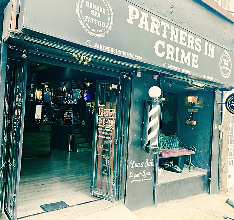 Fachada de Partners in Crime en Av. División del Norte 14, con la puerta de herrería abierta y el poste de barbero