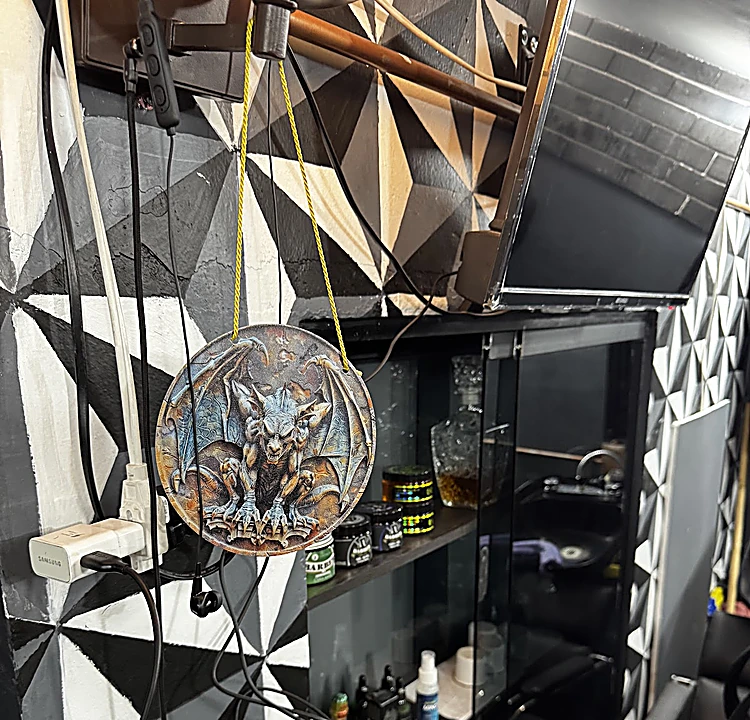 Muro de mosaico geométrico blanco y negro con un medallón de gárgola colgado junto a la repisa de productos